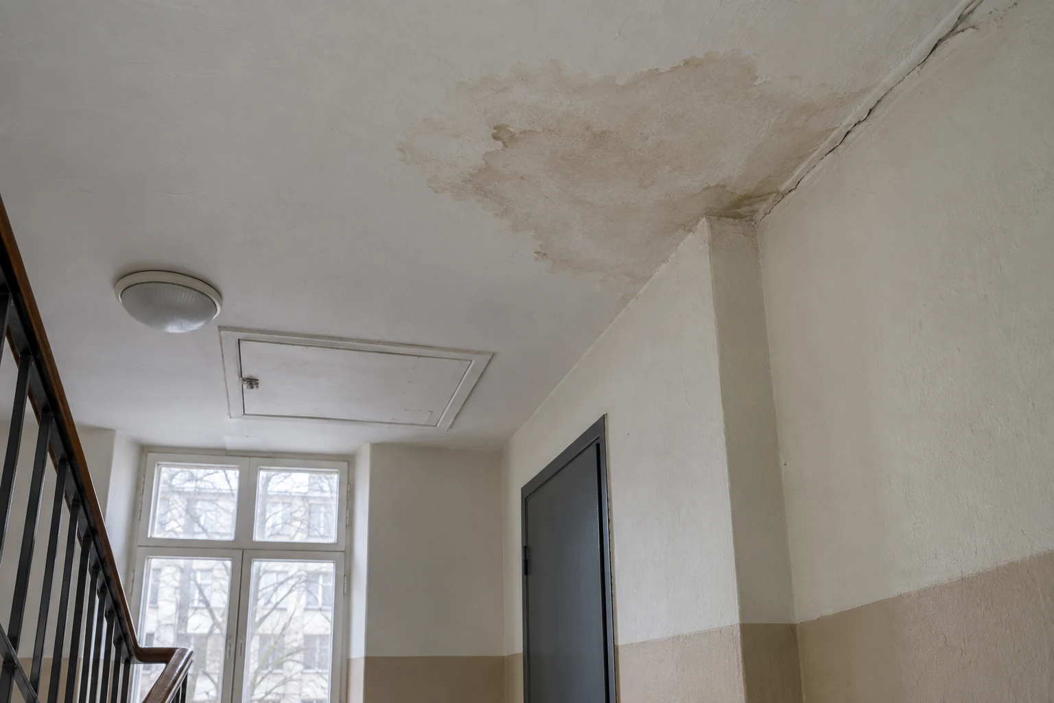 След протечки на потолке верхней лестничной площадки рядом с наружной стеной и люком доступа